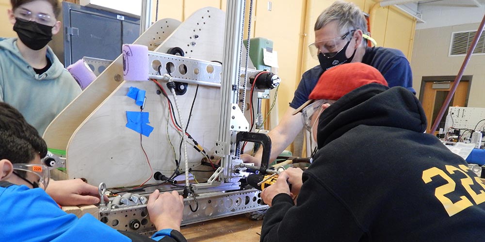 A picture of students and a mentor building a robot.